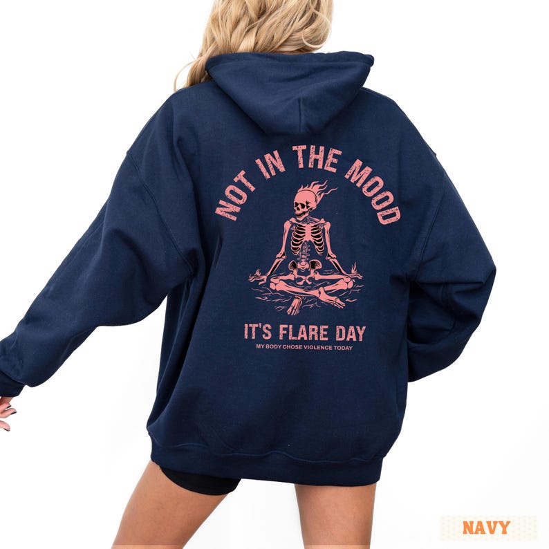 unisex chronic illness hoodie in color navy. Graphic of a pink skeleton in flames with a phrase not in the mood its flare day in grunge font in pink.