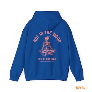 unisex chronic illness hoodie in color royal blue. Graphic of a pink skeleton in flames with a phrase not in the mood its flare day in grunge font in pink.