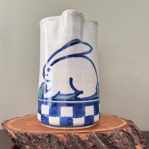 May include: A white ceramic mug with a black handle and the text "But First, Coffee" in a handwritten style. The mug is on a white surface. The mug is approximately 4 inches tall.