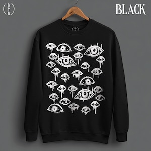May include: A black crewneck sweatshirt featuring a white graphic print of multiple eyes with dripping details. The word BLACK is printed in the upper right corner, and a circular logo with the letters BTD is in the upper left corner.