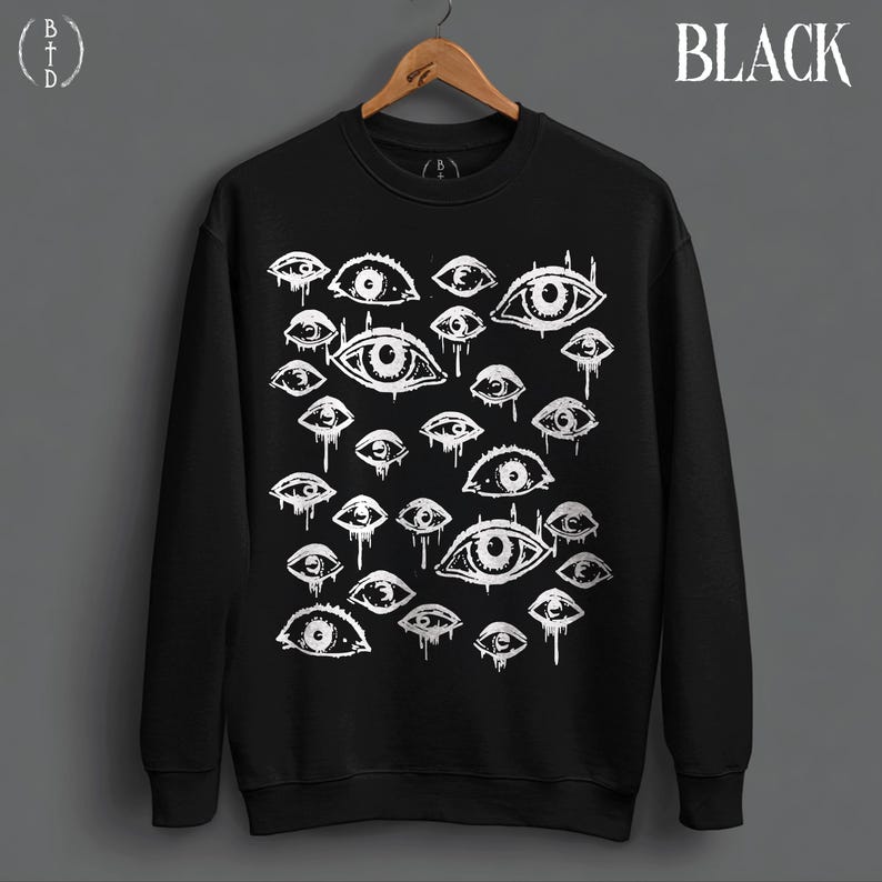 May include: A black crewneck sweatshirt featuring a white graphic print of multiple eyes with dripping details. The word BLACK is printed in the upper right corner, and a circular logo with the letters BTD is in the upper left corner.