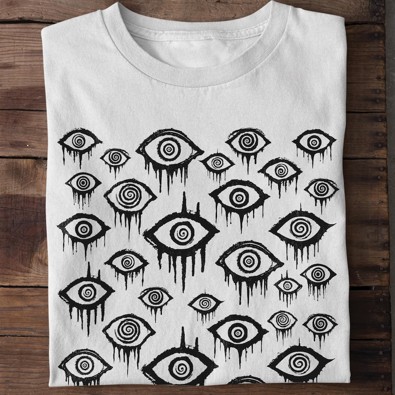 May include: White t-shirt featuring a black and white print of numerous stylised eyes with swirling patterns. The eyes are dripping with black paint.