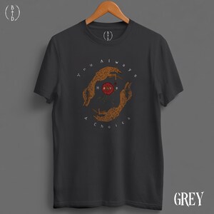May include: Dark grey t-shirt with a circular graphic featuring two stylized cheetahs and a red flower. The text "You always have a choice" surrounds the design. The shirt has short sleeves and a crew neck.