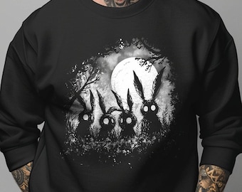 May include: A black crewneck sweatshirt featuring a white graphic print of four silhouetted rabbits with glowing eyes standing in a forest under a large full moon. The design is centered on the chest, showcasing a detailed, dark, and atmospheric illustration.