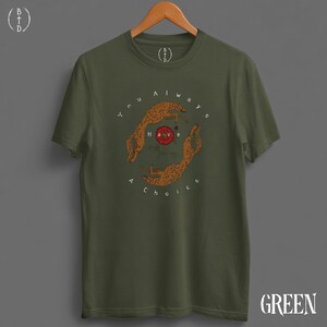 May include: Olive green t-shirt with a circular graphic featuring two cheetahs and the text "You always have a choice." The graphic is in shades of brown and red. The word "GREEN" is printed in white at the bottom right.