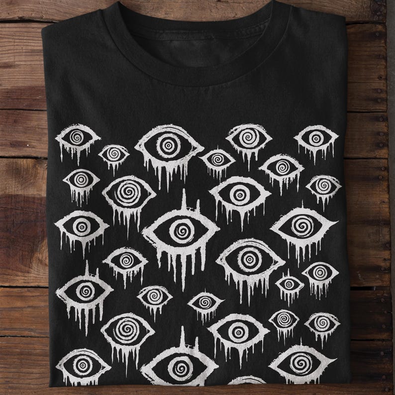 May include: Black t-shirt with a white repeating pattern of stylised eyes with spiral pupils. The eyes are dripping with white paint.