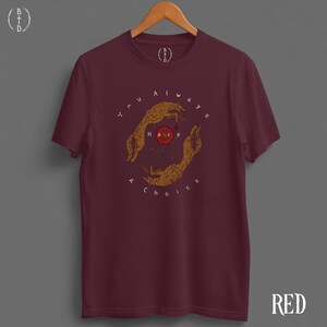 May include: A maroon t-shirt with a graphic design featuring two stylized hands encircling a red rose. The text "You always have a choice" is printed around the hands. The word "RED" is printed in the bottom right corner.