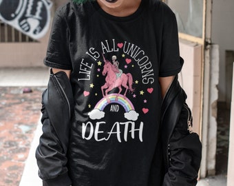 May include: Black t-shirt with a graphic print of a skeleton riding a pink unicorn with a rainbow and the text "Life is all unicorns and death".