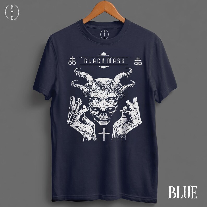 May include: A dark blue short-sleeve t-shirt featuring a white graphic print of a horned skull with hands raised on either side. The text "BLACK MASS" is printed above the skull, flanked by two Leviathan cross symbols and a small cross below.