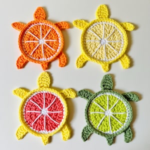 Peut inclure: Quatre dessous-de-verre en forme de tortue crochetés avec différents motifs de fruits d'agrumes. Les dessous-de-verre sont jaunes, orange, verts et roses avec des points blancs.