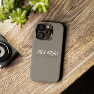May include: A gray phone case with a camera lens cutout and the text "Mid Night" in white lettering. The text "ミッドナイト クラブ" is also printed in white below the text "Mid Night".