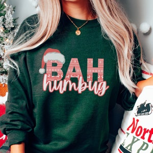 May include: Green Christmas sweatshirt with a red Santa hat and the text "BAH humbug" in red and white.