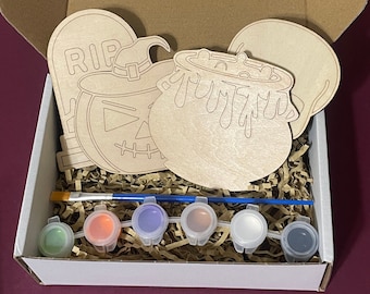 May include: A Halloween craft kit with wooden cutouts of a pumpkin, a cauldron, a tombstone, and a ghost. The kit includes six small paint pots in green, orange, purple, white, and black, and a paintbrush.