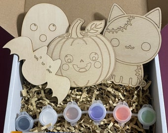 May include: A set of four wooden Halloween-themed paint-by-number kits featuring a ghost, a pumpkin, a bat, and a cat. The kit includes six small paint pots in various colors and a paintbrush.
