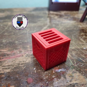 May include: A red plastic crate with a grid pattern and five slots on the top. The crate is about 3 inches tall.