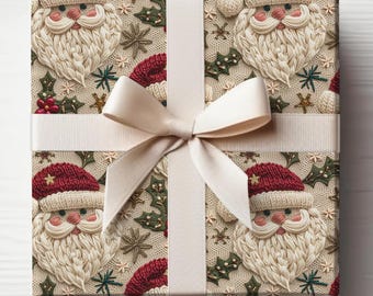 Op de afbeelding: Een crèmekleurige cadeaudoos met een wit satijnen lint. De doos is ingepakt in papier met een herhalend patroon van geborduurde kerstmangezichten met rode gebreide mutsen en hulsttakken.