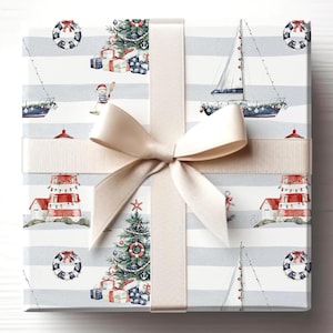 May include: A square gift box wrapped in nautical-themed paper with a cream ribbon and bow. The paper features sailboats, Christmas trees, lighthouses, and life preservers on a striped background. The bow is centered on the top.