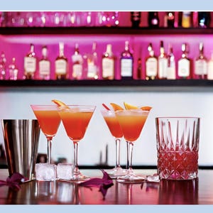 May include: A cocktail recipe called "Mezcaliente" with ingredients listed: 1 oz Sorrel, 2 oz Mezcal, 1 oz Passion Fruit Liqueur, 1 oz Triple Sec, 0.5 oz Lime Juice. The recipe instructs to combine all ingredients, shake with ice, strain into a coupe glass, and garnish with a candied blood orange slice. The image shows a bar setting with a bottle of Sorrel liqueur, a coupe glass filled with a red cocktail, and a candied blood orange slice.