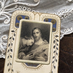 May include: A vintage religious card with a black and white image of Jesus and a disciple. The card has a gold and blue decorative border.