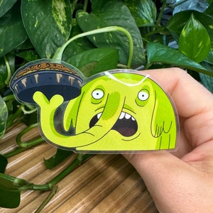 May include: A green cartoon elephant with a surprised expression holds a pie in its trunk. The elephant is a sticker with a clear background.