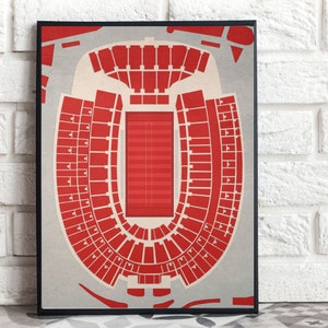 May include: A red and white print of a football stadium seating chart. The stadium is a horseshoe shape with a football pitch in the centre.