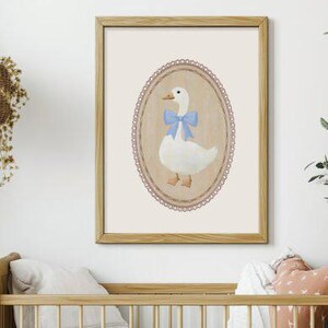 May include: A framed illustration of a white goose with a blue bow, set against a cream background with a decorative lace border.