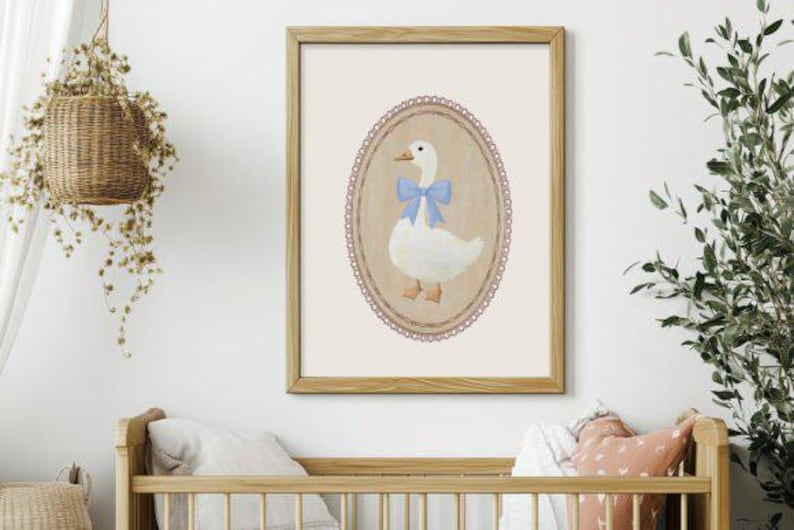 May include: A framed illustration of a white goose with a blue bow, set against a cream background with a decorative lace border.