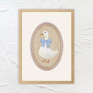 May include: A framed illustration of a white goose with a blue bow, set against a beige background with a pink lace border.