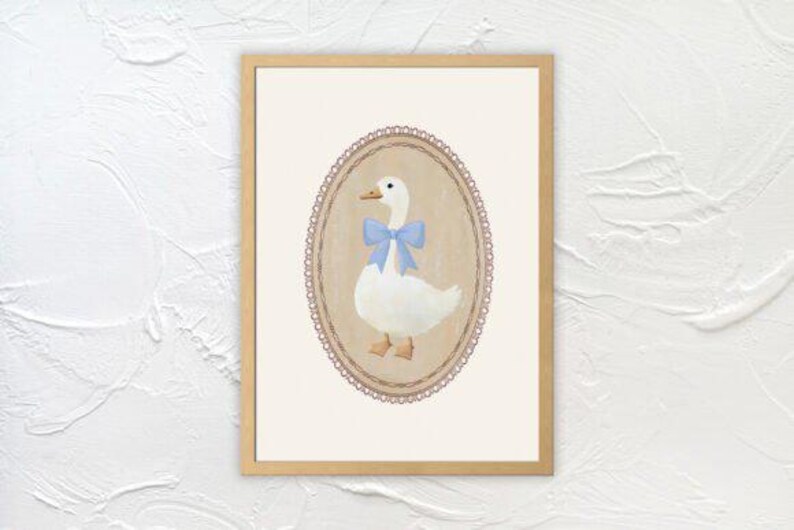 May include: A framed illustration of a white goose with a blue bow, set against a beige background with a pink lace border.