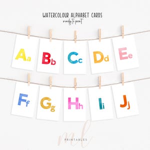 May include: A display of white cards, each featuring a watercolour letter of the alphabet from A to J, suspended by wooden pegs on a string. The letters are in vibrant colours. The text at the top reads "WATERCOLOUR ALPHABET CARDS ready to print."