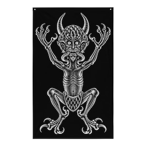 Puede incluir: Un tapiz de pared rectangular negro con una ilustración de líneas blancas de una criatura con cuernos y garras, cabeza escamosa, ojos muy abiertos y expresión de dientes descubiertos. La figura aparece en cuclillas con los brazos en alto.