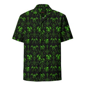 Puede incluir: Una camisa de manga corta con botones en color negro que presenta un patrón repetitivo de figuras de gárgolas aladas en verde neón brillante y símbolos geométricos intrincados. La camisa cuenta con un cuello clásico y cierre frontal.