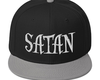 Puede incluir: Una gorra de béisbol negra y gris con la palabra "SATAN" bordada en blanco en la parte delantera.