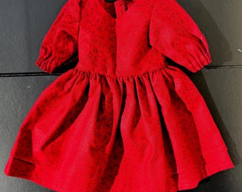 Könnte beinhalten: Ein leuchtend rotes Kleid mit V-Ausschnitt und kurzen, gepufften Ärmeln. Das Kleid hat einen gerafften Rock und ein dezentes Blumenmuster. Der Stoff scheint ein weiches, strukturiertes Material zu sein. Das Kleid ist für ein Kind konzipiert.