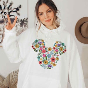 a woman wearing a white mickey mouse hoodie