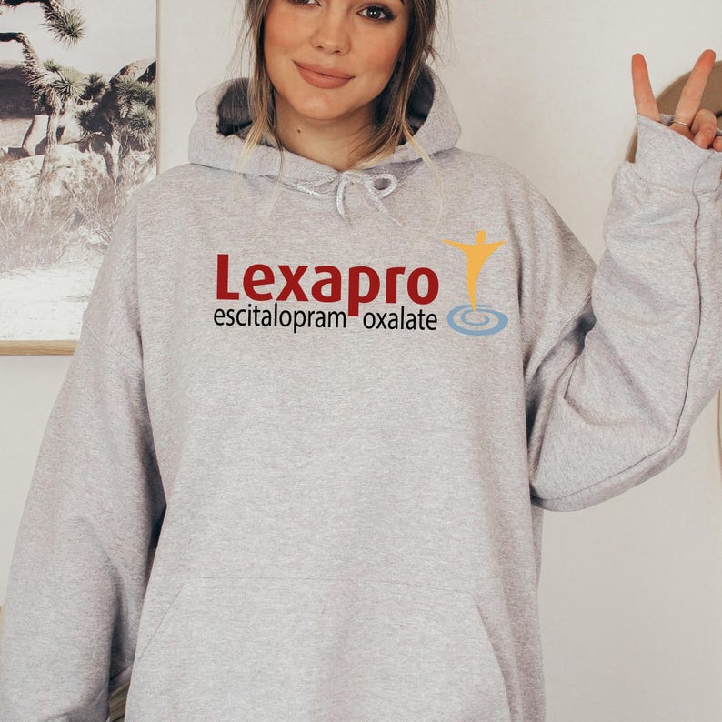 a woman in a gray sweatshirt holding up a peace sign
