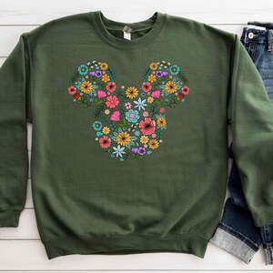 a green sweatshirt with a mickey mouse design on it
