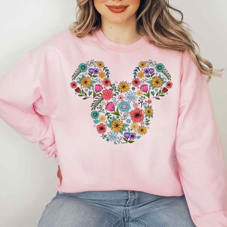 a woman wearing a pink mickey mouse sweatshirt