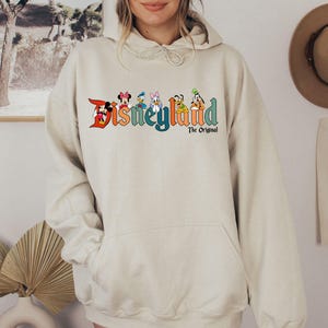 a woman wearing a white disney land hoodie