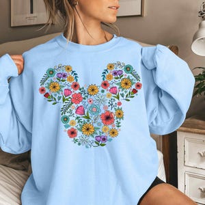 a woman wearing a blue mickey mouse sweatshirt