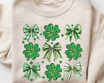 May include: A beige sweatshirt with a green shamrock and bow pattern. The text "SAND" is in the upper right corner of the image.