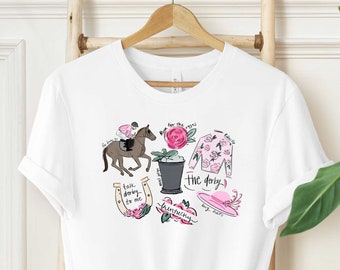 Könnte beinhalten: Weißes T-Shirt mit einem pinkfarbenen und schwarzen Grafikdesign mit einem Pferd, einem Jockey, einem Hufeisen, Blumen und dem Text "The Derby's" und "Race, darling, race to me".