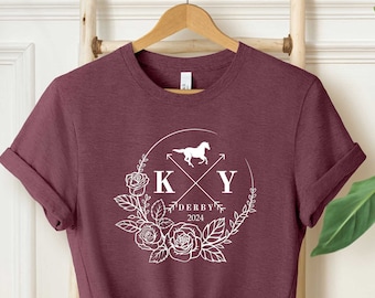 May include: A maroon t-shirt with a white graphic design of a horse, flowers, and the letters "KY" with the text "Derby 2024" underneath.