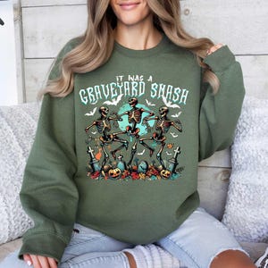 May include: A green sweatshirt with the text "It was a Graveyard Smash" and a graphic of three skeletons dancing in a graveyard.