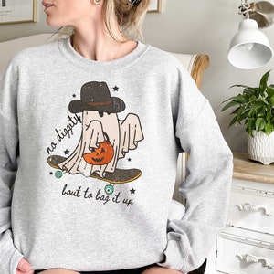 May include: A gray sweatshirt with a graphic of a ghost wearing a hat and holding a pumpkin. The ghost is skateboarding and the text "no diggity bout to bag it up" is printed below the ghost.