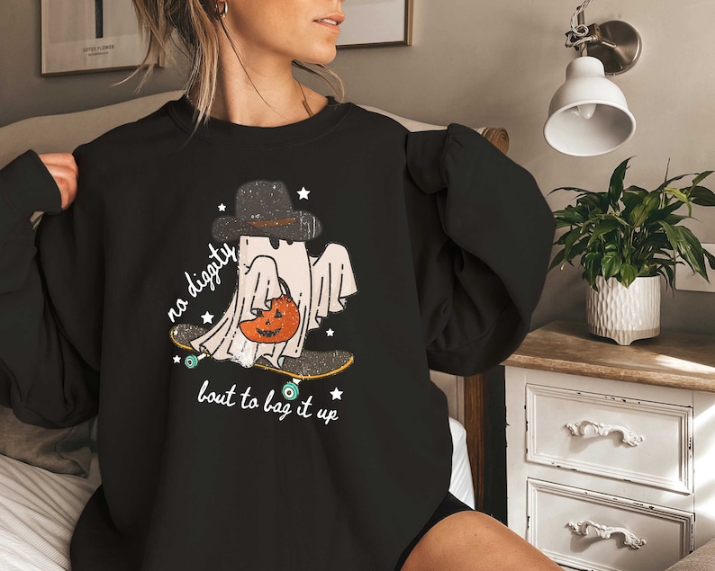 May include: Black sweatshirt with a graphic of a ghost skateboarding and holding a pumpkin. The text on the sweatshirt reads "no digity bout to bag it up".