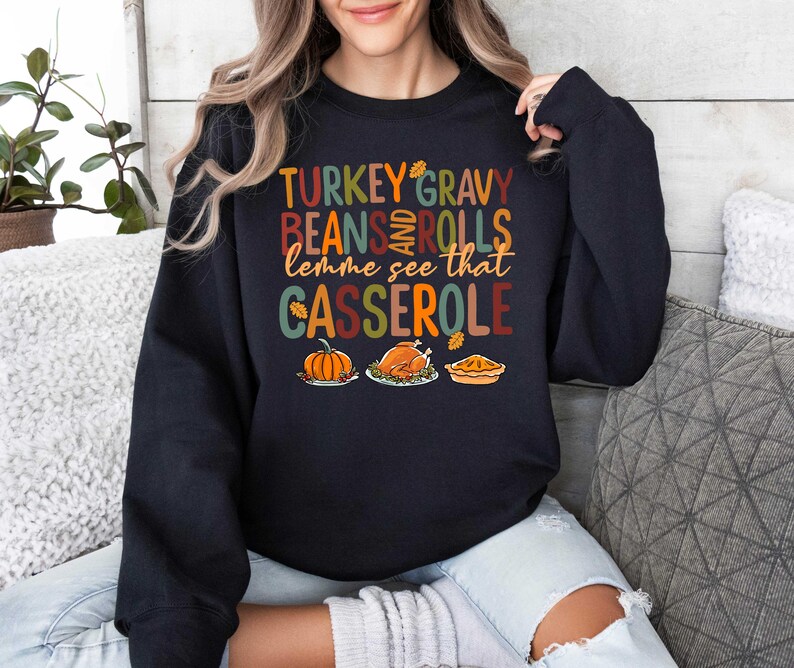May include: Black sweatshirt with a Thanksgiving-themed graphic that says "Turkey Gravy Beans and Rolls lemme see that Casserole". The graphic features a pumpkin, a turkey, and a pie.