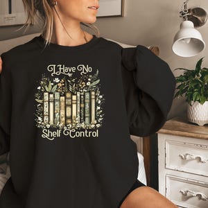 K&ouml;nnte beinhalten: Schwarzes Sweatshirt mit floralem Design und dem Text "I Have No Shelf Control".