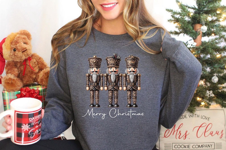 May include: A gray sweatshirt with a graphic of three nutcracker figurines wearing leopard print outfits. The text "Merry Christmas" is written below the figurines.