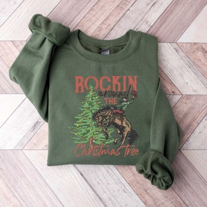 May include: A green sweatshirt with a Christmas tree design and the text "Rockin' around the Christmas Tree".